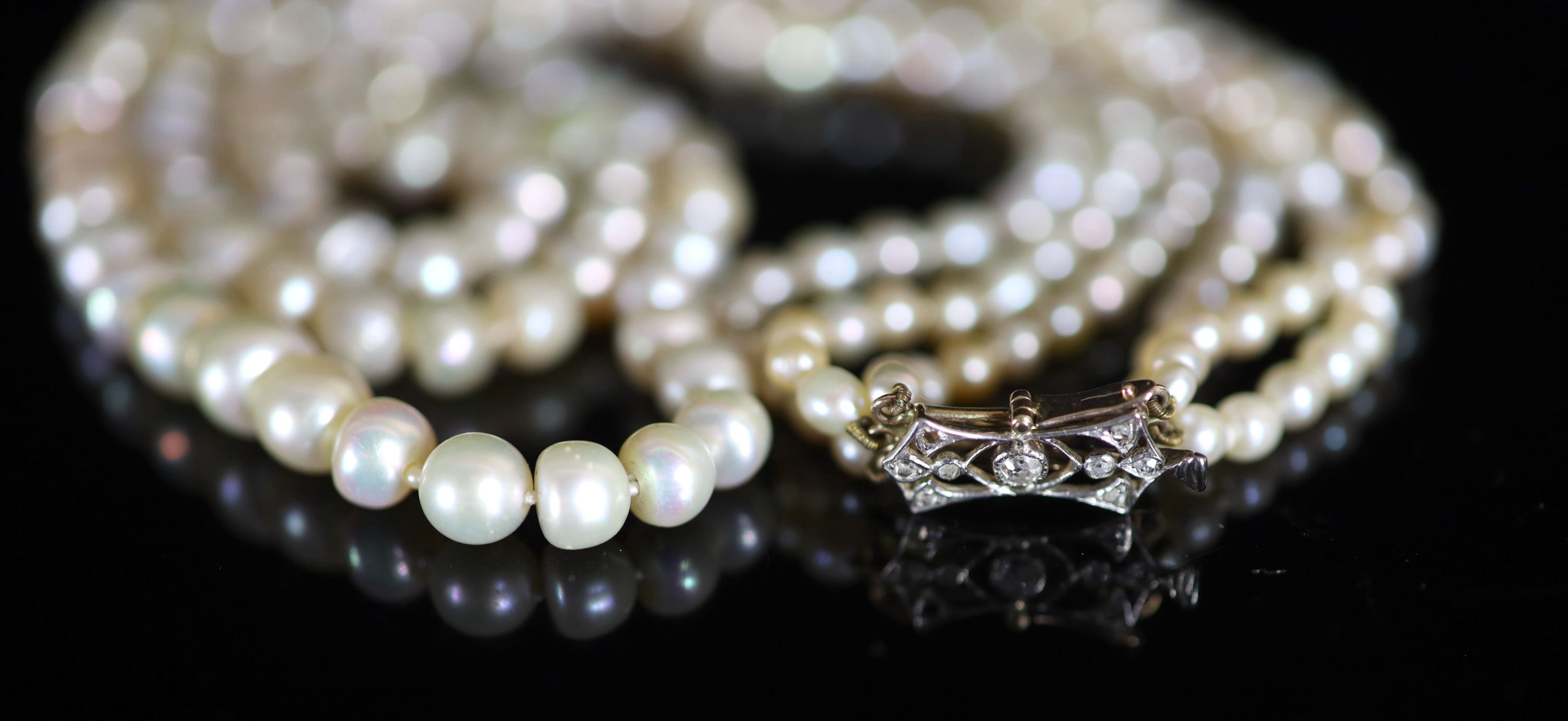 A three-row graduated pearl necklace with diamond-set openwork yellow metal clasp